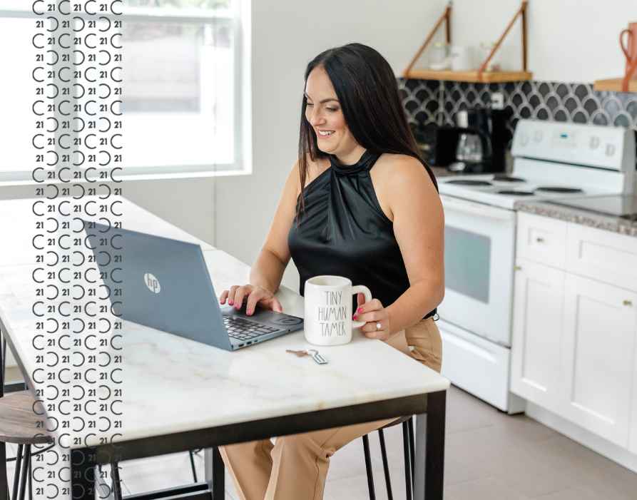 Century 21 real estate agent sitting at the kitchen counter on the computer